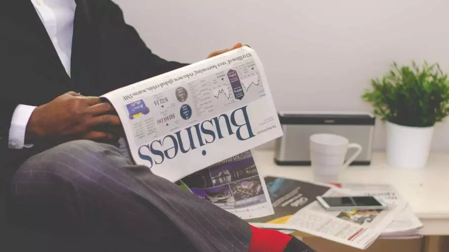 man reading newspaper while sitting near table with 935979