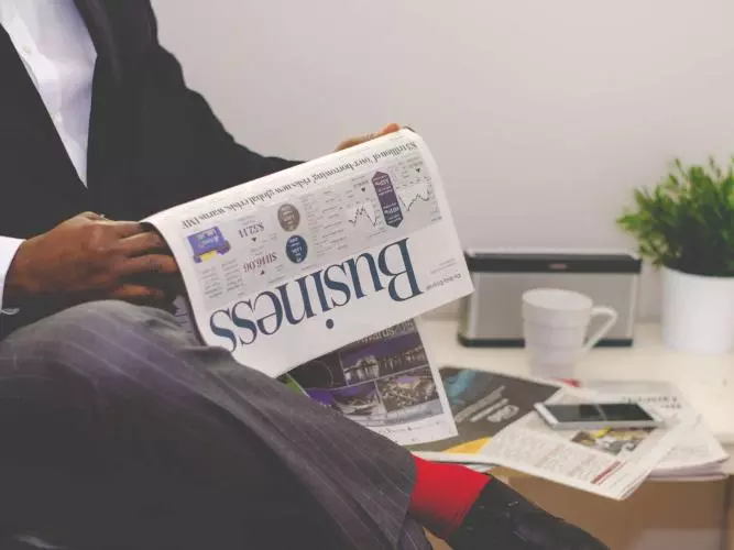 man reading newspaper while sitting near table with 935979