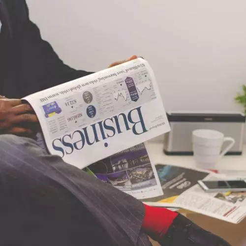 man reading newspaper while sitting near table with 935979